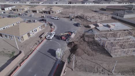 un avión no tripulado en círculo captura una carretilla elevadora extensible en acción, bajando suavemente una carga de madera en un sitio de construcción de viviendas dentro de un nuevo vecindario