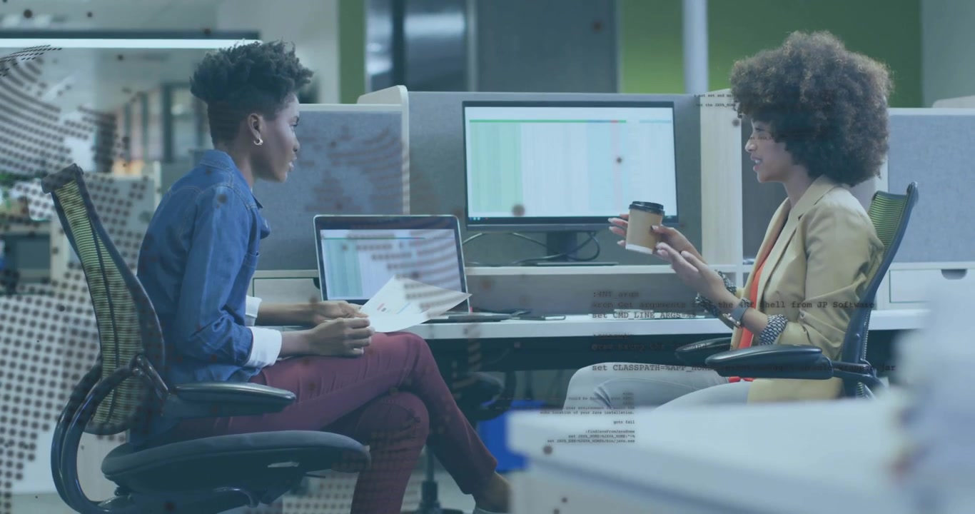 Woman handing coffee cup to colleague reviewing business spreadsheet on laptop screen