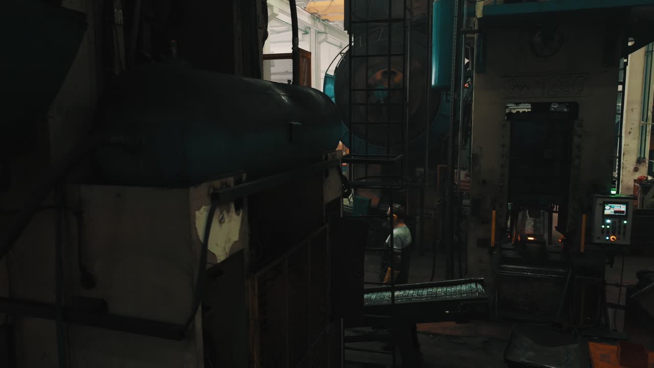 Industrial manufacturing process with a worker operating heavy machinery.