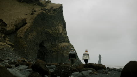 couple walking on a black sand beach in iceland