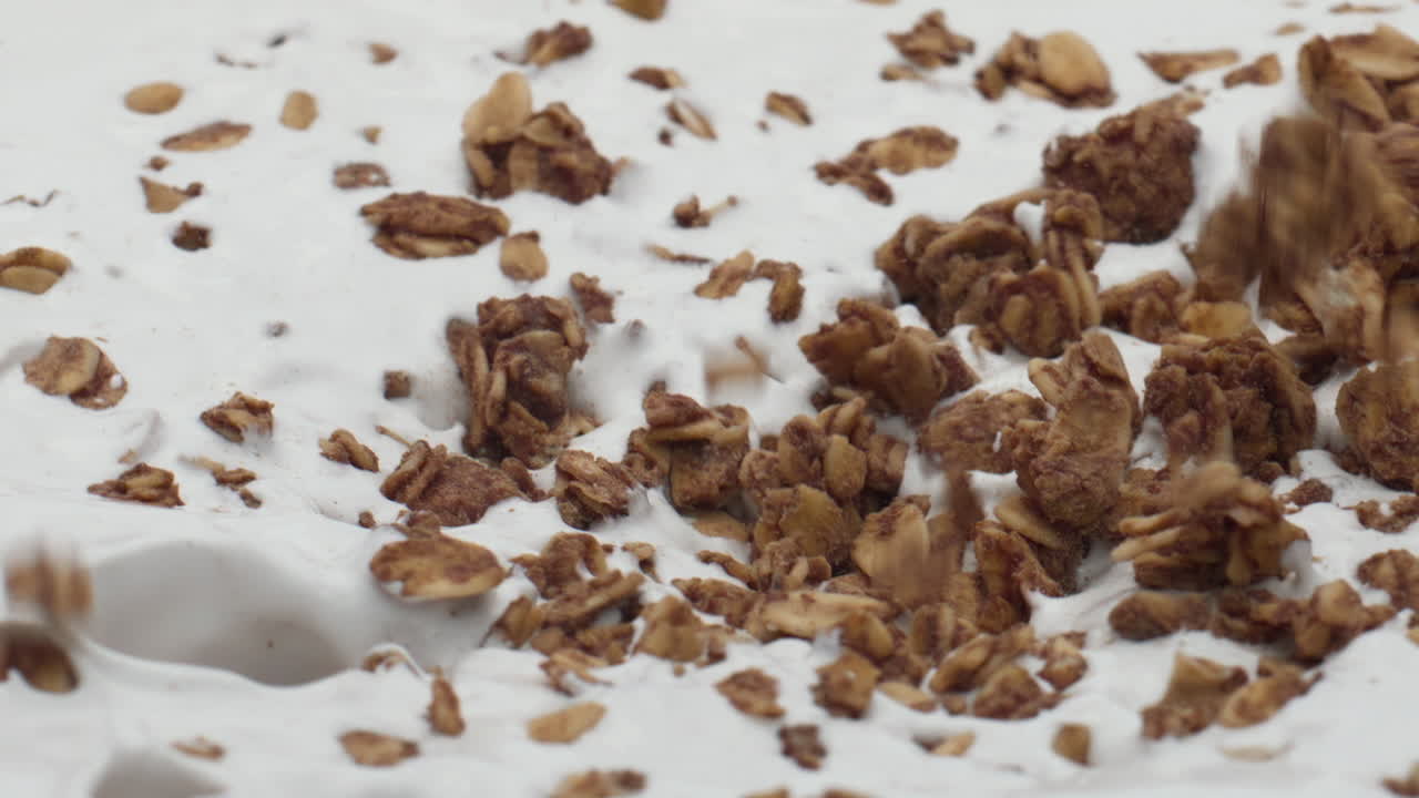 Versare granola e yogurt fresco in super slow motion, primo piano. Colazione nutriente.