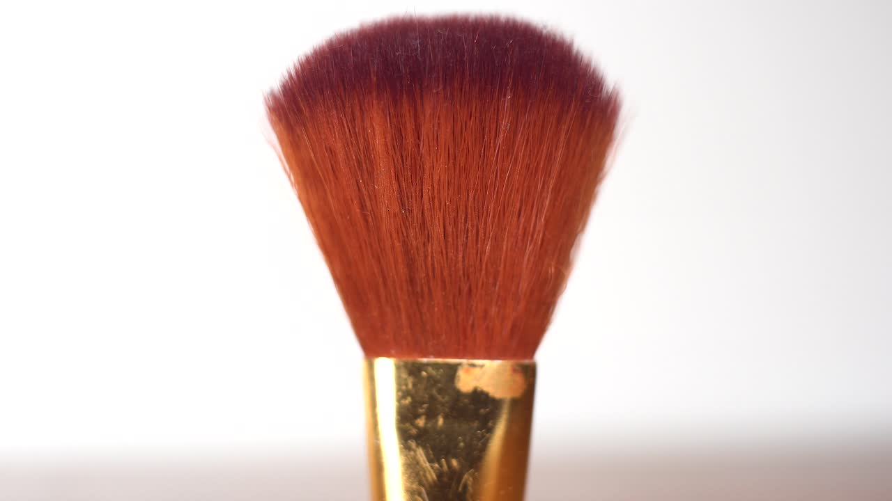 Extreme Close-up of make up brush applicator with gold base as slight sweeps across it dramatic cinematic