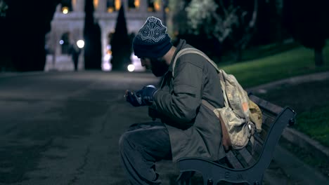 homeless walking in the city park at night ,countings his alms