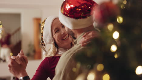 una pareja bailando junto al árbol de navidad.