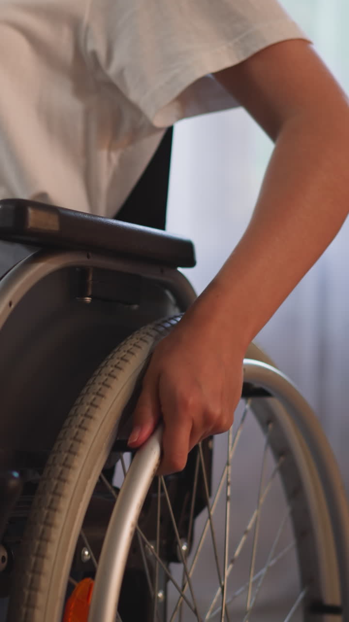 mujer con discapacidad física trata de girar ruedas con las manos para moverse en silla de ruedas en un fondo borroso. persona con discapacidad se mueve en la sala de estar de cerca