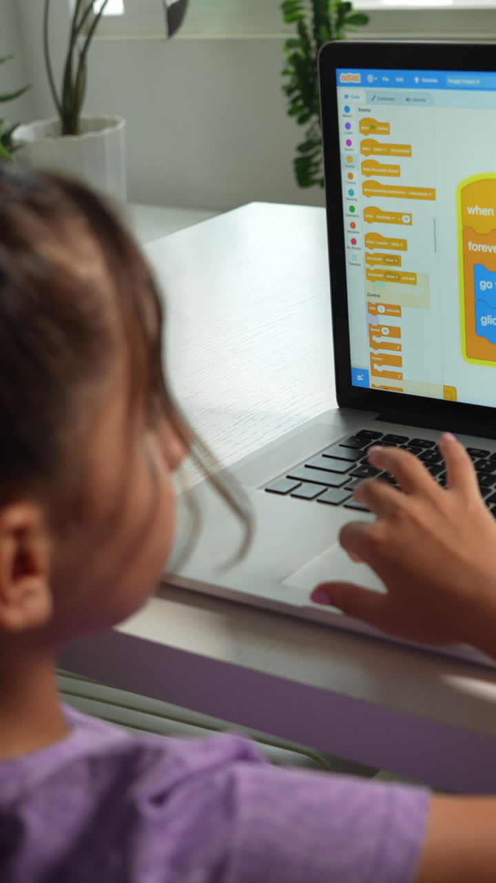 A child in a purple shirt engaged in STEM programming on a laptop, bright natural light, indoor setting, close-up, vertical video, ideal for mobile and social media platforms
