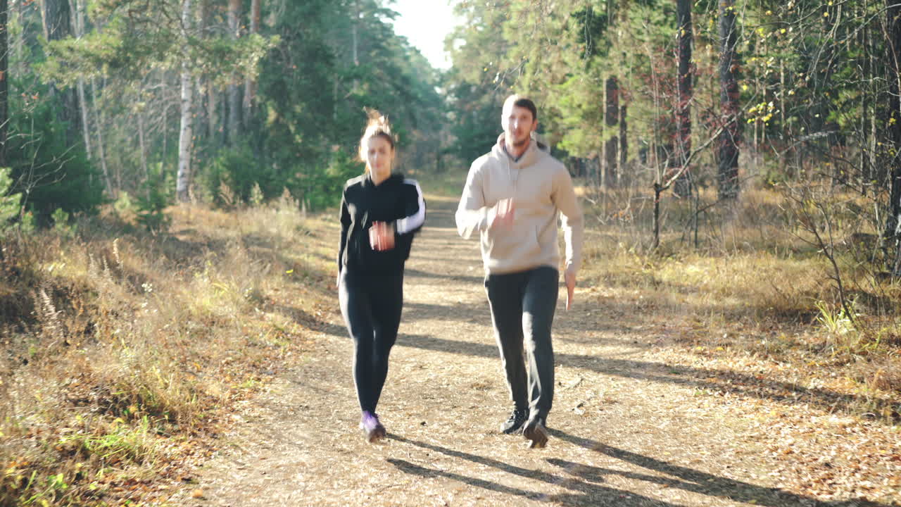 Coppia che fa jogging in un bosco autunnale