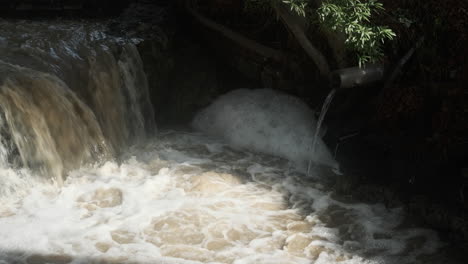 Wasser-Sprudelt-Aus-Einem-Bach-Und-Abflussrohren,-Die-Schaum-Bilden