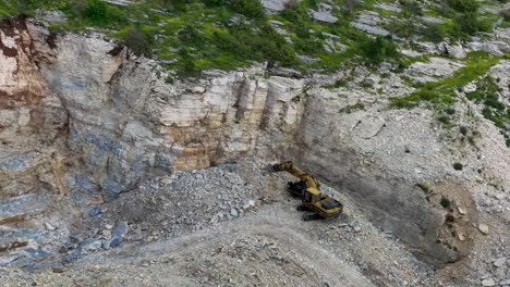 excavator parked in a quarry with rocks dug from the side of the mountain