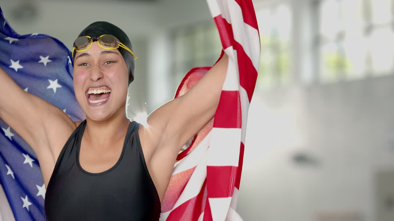 Celebrating victory, female swimmer holding flag and smiling in swimming pool area