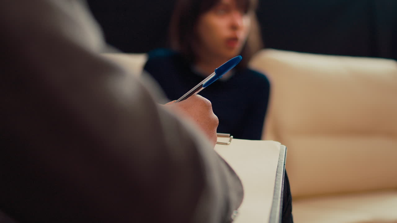 Male therapist taking notes on papers at psychology session