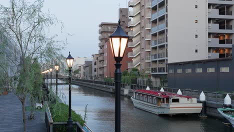 a shot capturing the stylish streetlights on the promenade along the kita-jūkken-gawa river at dusk. the streetlights are lit, and their light is reflected on the canal's surface