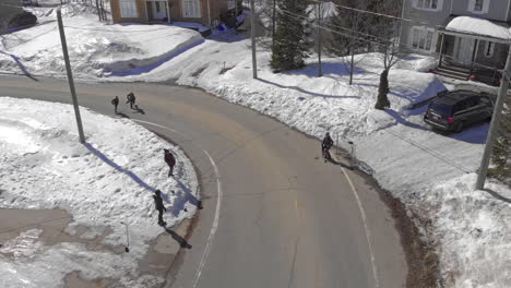 Epic-Drone-Pullback-from-Young-Kids-Playing-in-Snow-Covered-Streets-to-Reveal-Snow-Covered-Residential-Rooftops,-Aerial