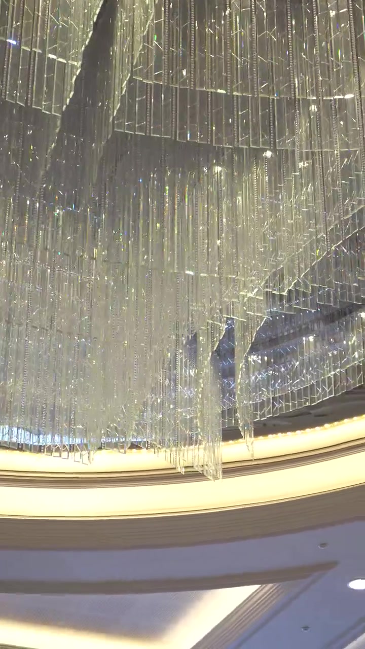 Stunning footage of a luxurious cascading crystal chandelier illuminating a grand ballroom. Perfect for luxury event, wedding, or high-end real estate videos.