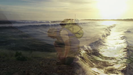 male hiker kneeling on pebble beach at sunset, showing animated heart rate chart for health