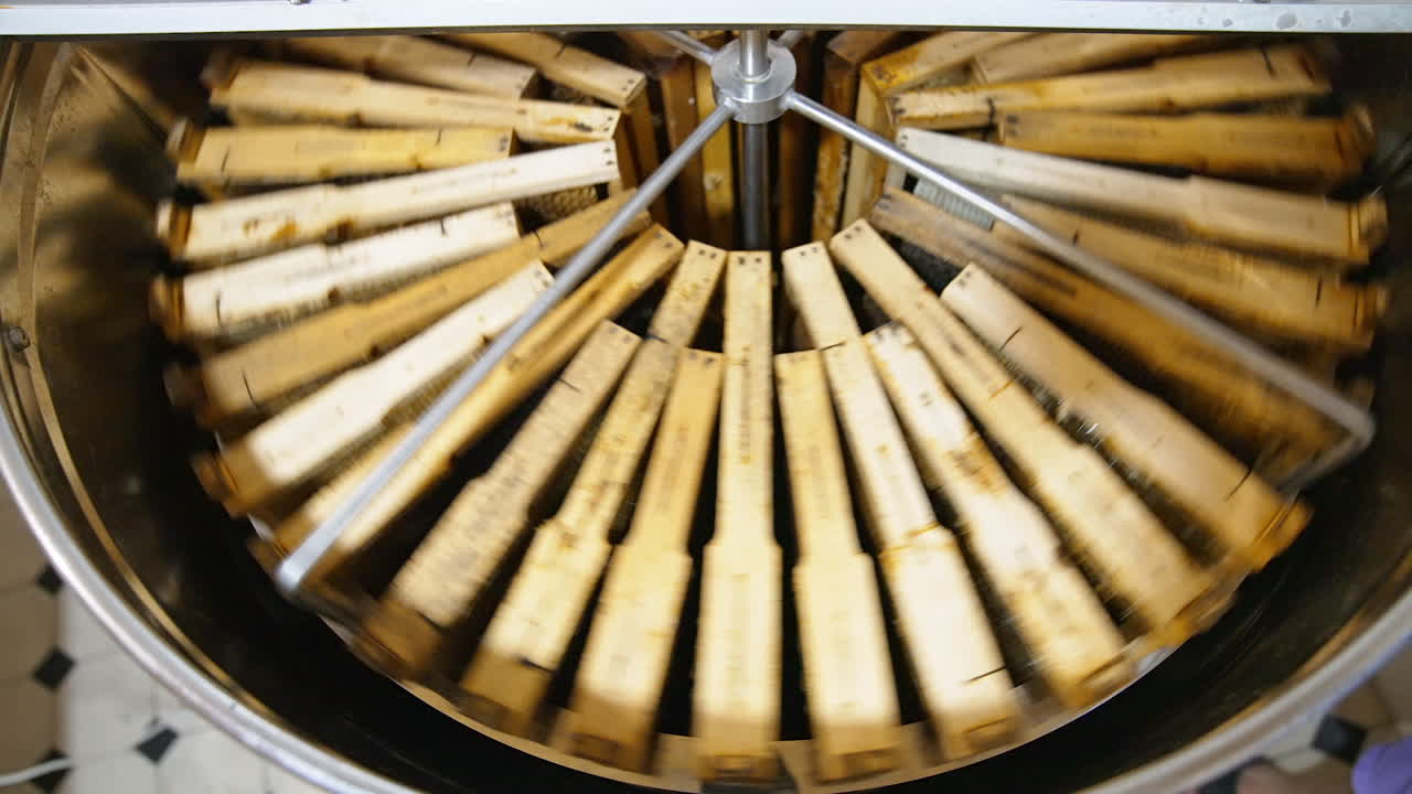 Centrifuge inside a metal barrel rotating and spinning honey frames. Extracting healthy product in special device.