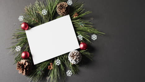 video of christmas decorations and white card with copy space on black background