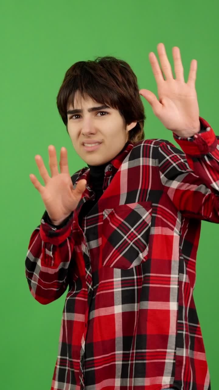 Young Person Expressing Caution and Fear with Hand Gestures on Green Screen