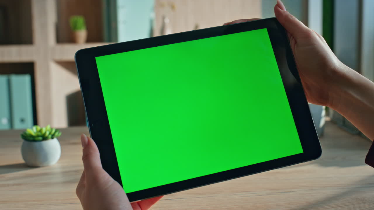 Unrecognizable student browsing video on green screen tablet at home close up.