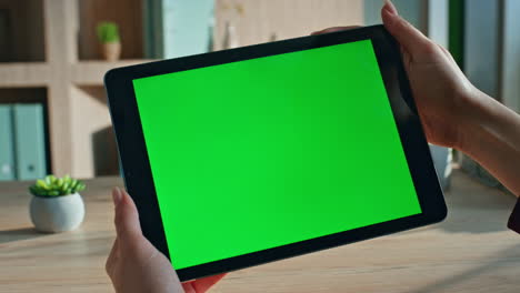 unrecognizable student browsing video on green screen tablet at home close up.