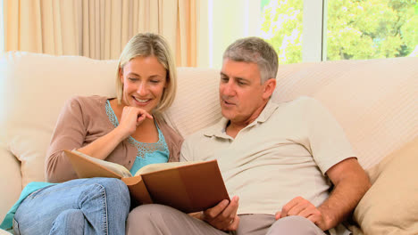 Couple-smiling-looking-at-a-photograph-album