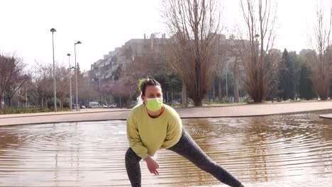 athlete woman doing stretching in the park after running and with a nice fountain behind