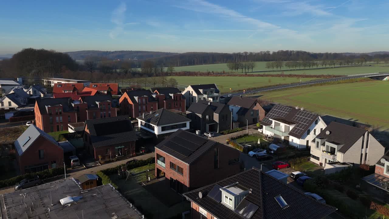 Droneflyvning over et moderne boligområde med luksushjem og solpaneler på taget. Solrig efterårsdag i en tysk by. Bredt dronebillede. Marker i det fjerne