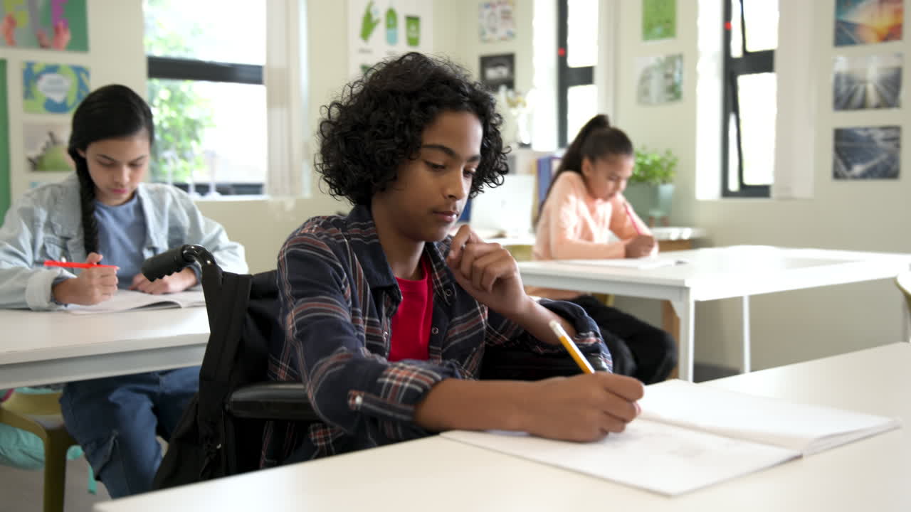 Multiracial students in classroom writing in notebooks, focused and engaged in schoolwork