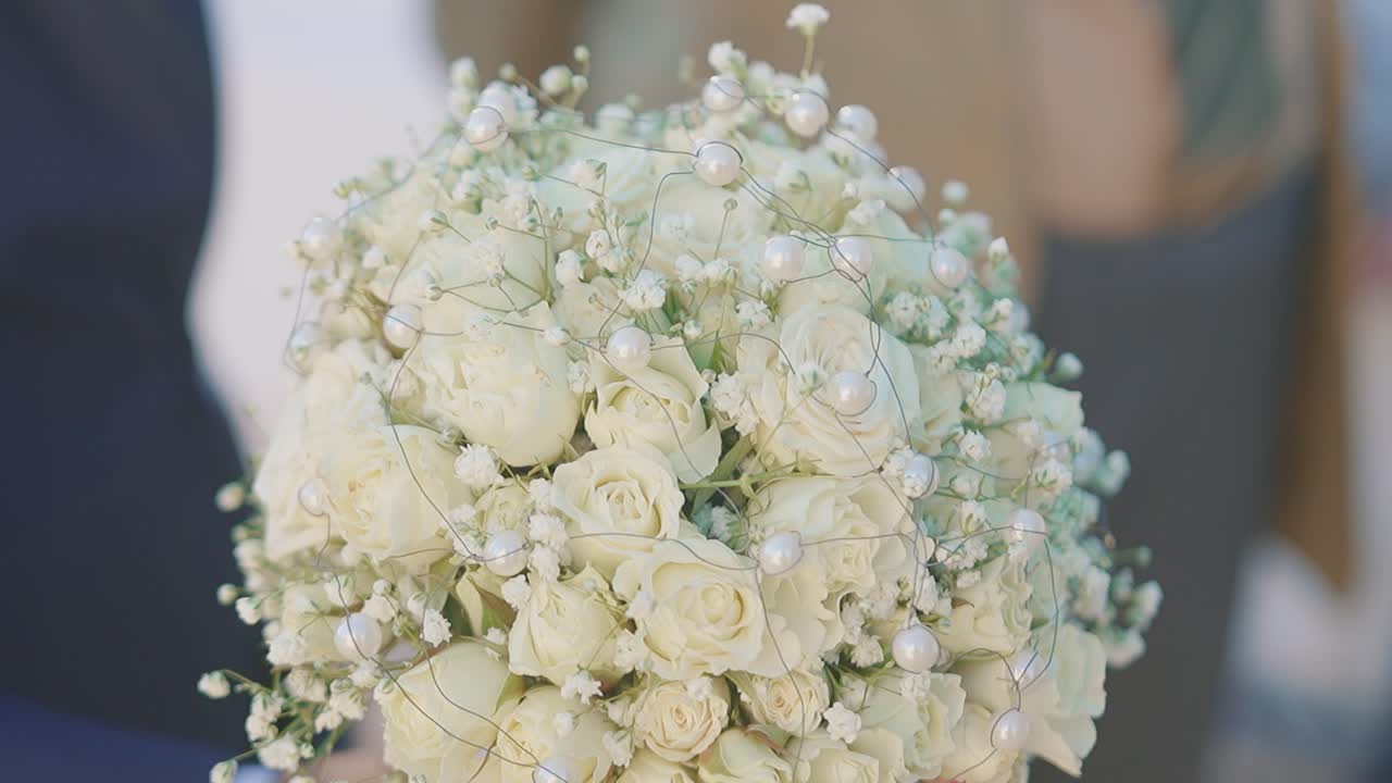 Splendido bouquet di rose bianche tenuto durante una cerimonia di matrimonio all'aperto