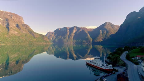 Ferry-Atracado-En-Un-Fiordo-En-Noruega-Con-La-Superficie-Del-Agua-Reflejando-El-Cielo-Y-El-Paisaje