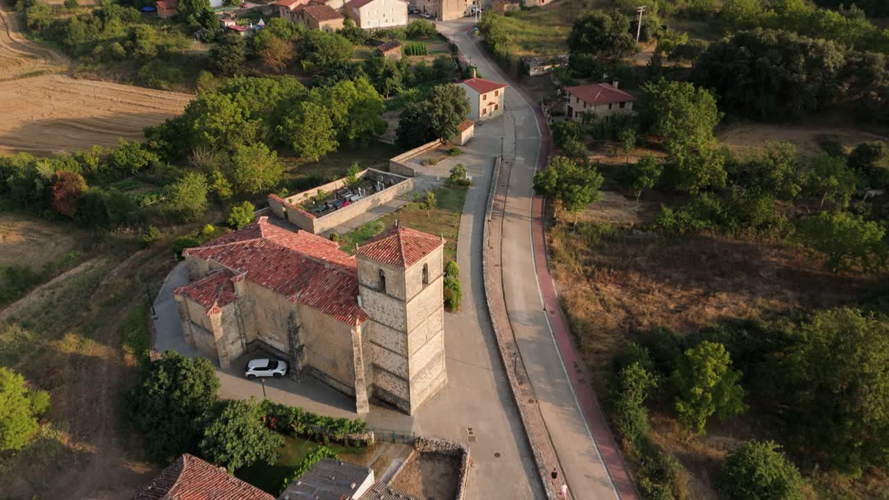 Overhead drone shot showing a village in a rural countryside's homes, church, and farmlands in Valderama, Burgos province in Spain.