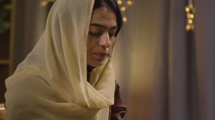 Young Muslim Woman Sitting Around Table At Home Drinking Water And Eating Meal Celebrating Eid