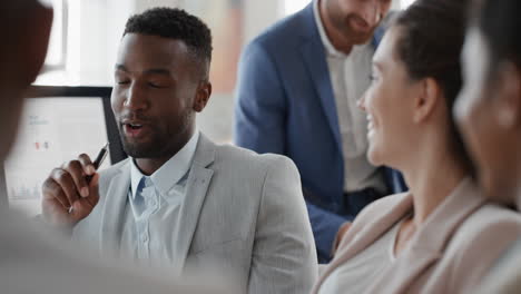 Hombre-De-Negocios-Afroamericano-Charlando-Con-Colegas-En-Una-Reunión-De-Oficina-Conversando-Compartiendo-Ideas-Con-Diversos-Grupos-Corporativos-En-El-Lugar-De-Trabajo