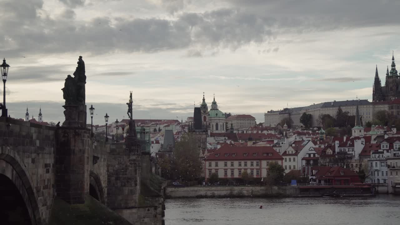 Ponte Carlo o Karlův most, vista laterale ravvicinata di giorno, panoramica a destra verso il Castello di Praga, uccelli in volo, atmosfera suggestiva