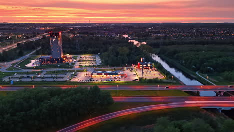 cars ride quickly by the highways illuminated by the blue and pinks lights at dusk. outskirts of the city in the netherlands. aerial view.