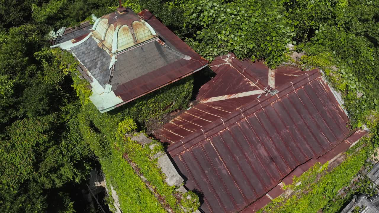 vista aérea cercana de una mansión abandonada, cubierta de hiedra en wakayama, japón.