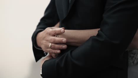 Grooms-hand-with-a-golden-ring-stroking-brides-hand-gently-while-bride-is-hugging-him-from-behind