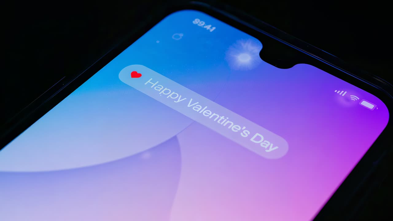 Camera shifting phone screen in dark studio, showing Happy Valentine's Day bubble with red heart