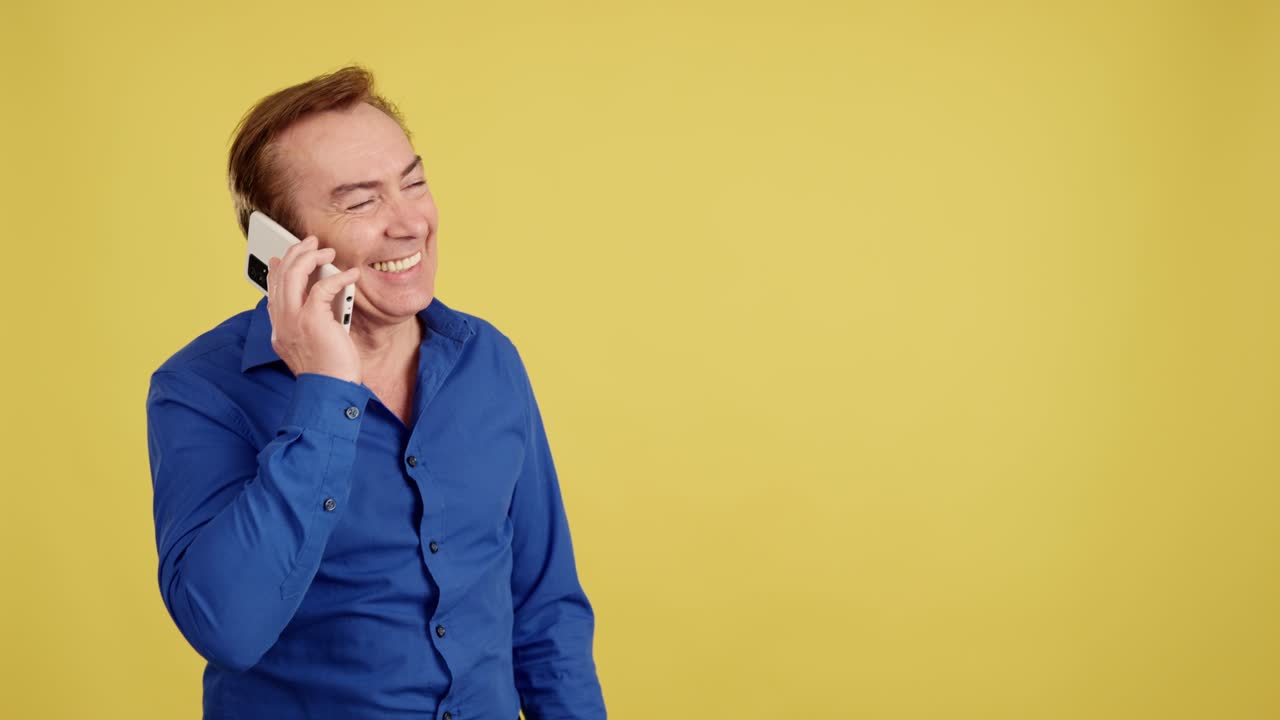 Happy Man Talking on Phone Against Yellow Background