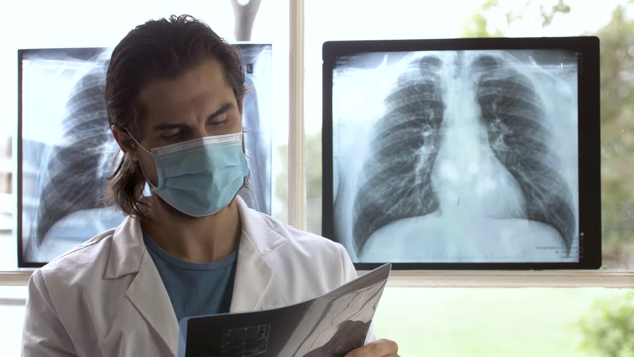 un guapo técnico de rayos x comprobando cuidadosamente el escáner de rayos x de la zona torácica