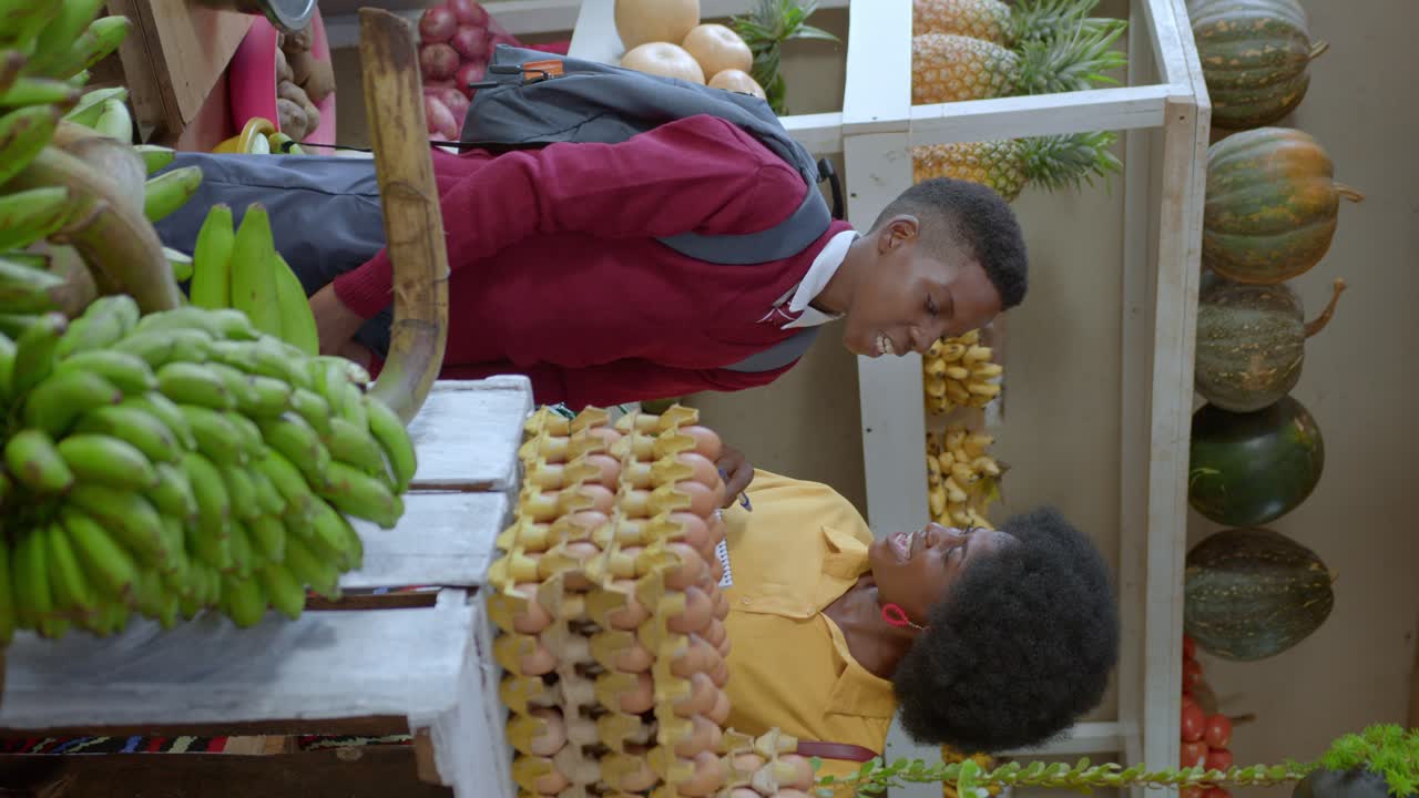 Tampilan Vertikal Seorang Wanita dan Anak Laki-laki di Dalam Kios Buah di Pasar Kampala di Uganda, Afrika