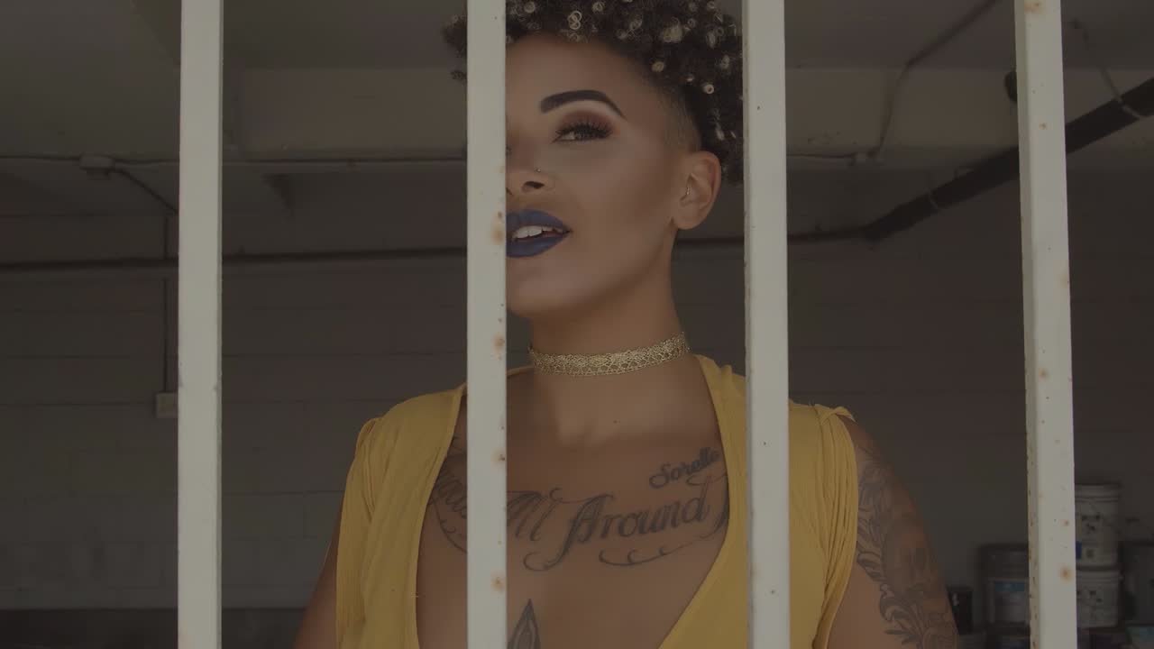 primer plano de un modelo tatuado detrás de parrillas blancas