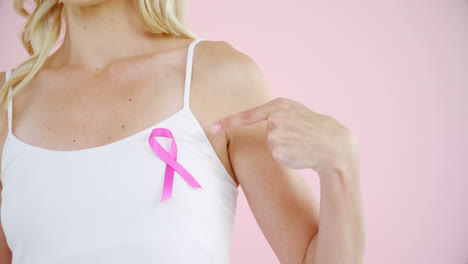 Mid-section-of-woman-showing-breast-cancer-awareness-ribbon