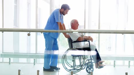 doctor holding senior patient on wheelchair in passageway