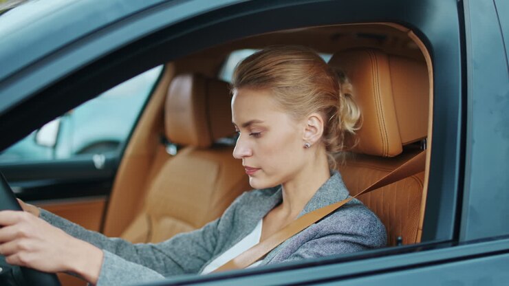 Primo piano di una donna alla guida che allaccia la cintura di sicurezza in auto. Donna seduta sul sedile anteriore