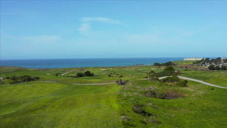 aerial drone shot of a lawnmower cutting the grass at a gold course in half moon bay, california, usa