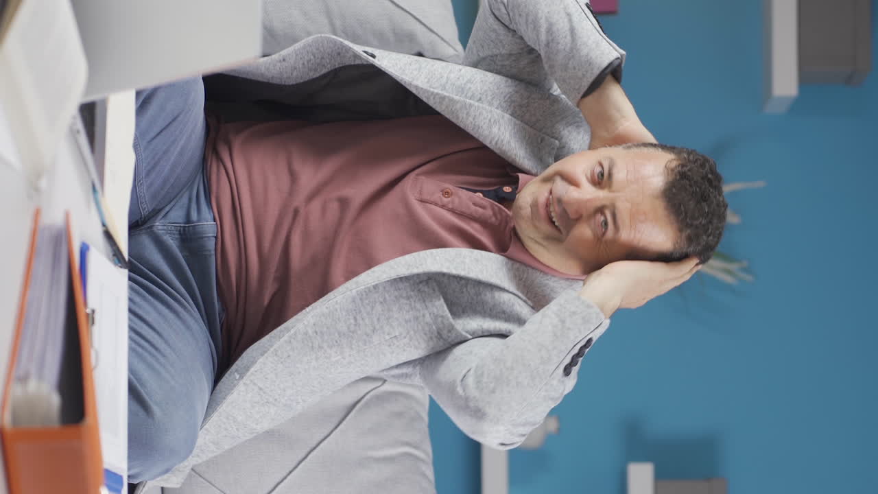 vídeo vertical de un anciano trabajador de oficina en casa mirando a la cámara con una cara feliz y sonriente.