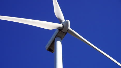 close-up view of a wind turbine's blades spinning against a blue sky background