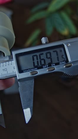 manos de ingeniero que utilizan una pinza de vernier para escalar la pieza metálica,