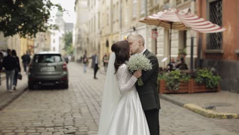 Newlyweds-portrait,-caucasian-groom-bride-walking,-embracing,-hugs-on-city-street,-wedding-couple